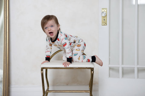 A girl wearing happy dumpling pjs is climbing on a step stool.