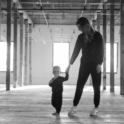 Mom and baby walk hand in hand wearing matching loungewear sets. 
